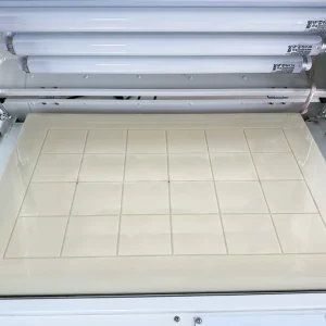 Vue de haut en bas à l'intérieur de l'unité d'exposition UV sous vide AP-200W, montrant la table à vide intégrée avec un quadrillage conçu pour une aspiration optimale. En dessous, les puissantes lampes UV assurent un contact précis pour le développement des plaques photopolymères.